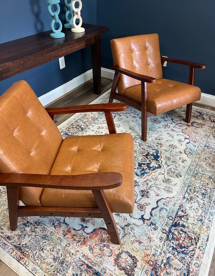 A pair of tan leather mid-century armchairs with wooden frames