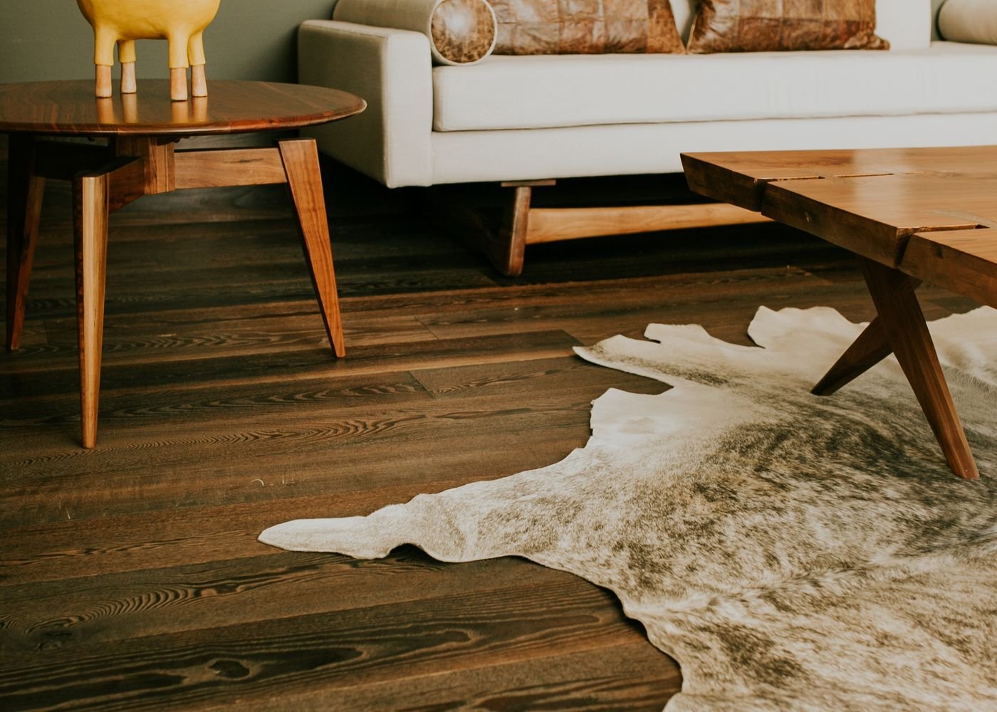 Walnut occasional tables and a hide rug in a warmly lit interior